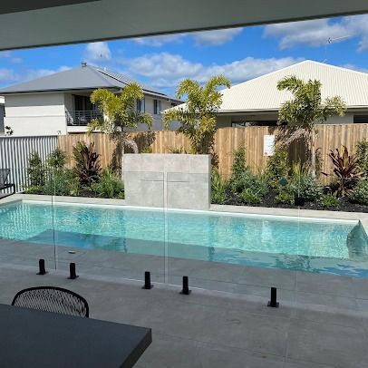 A Large Swimming Pool Is Surrounded By A Glass Fence — Ballina Pool Shop In Ballina, NSW