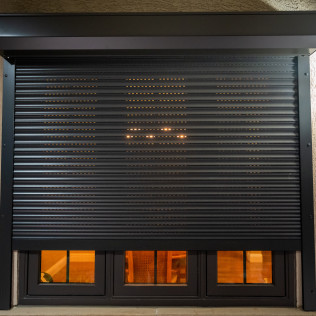 A window with a black roller shutter on it