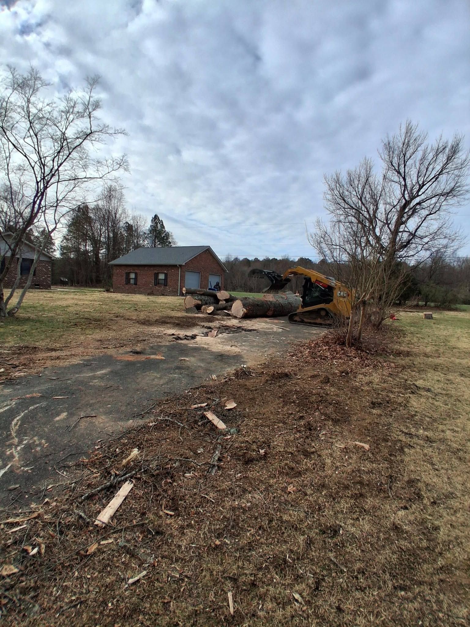 Burned debris and scorched ground near a brick house under a cloudy sky