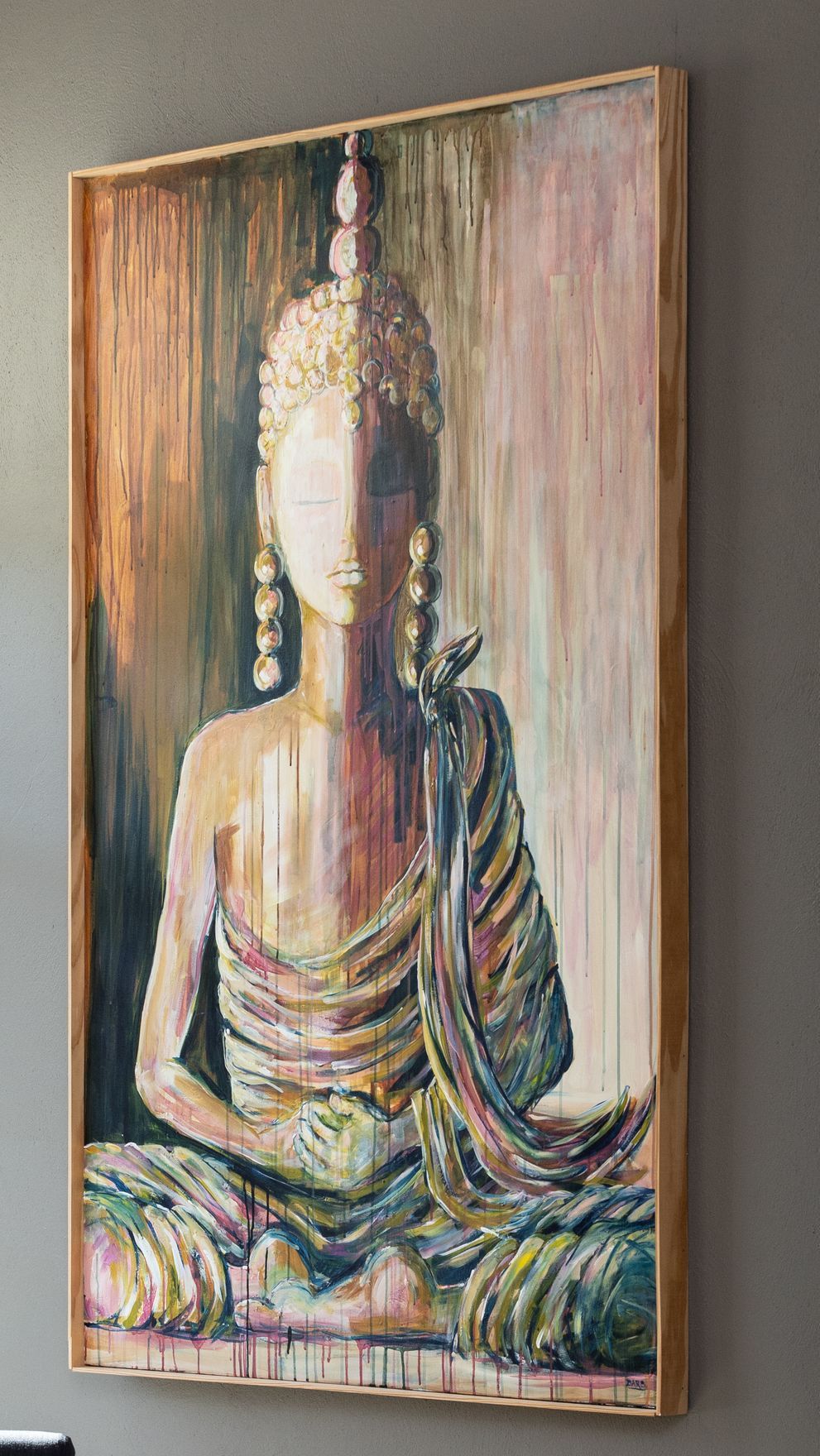 Abstract painting of a seated Buddha with gold robes and a textured, multicolored background