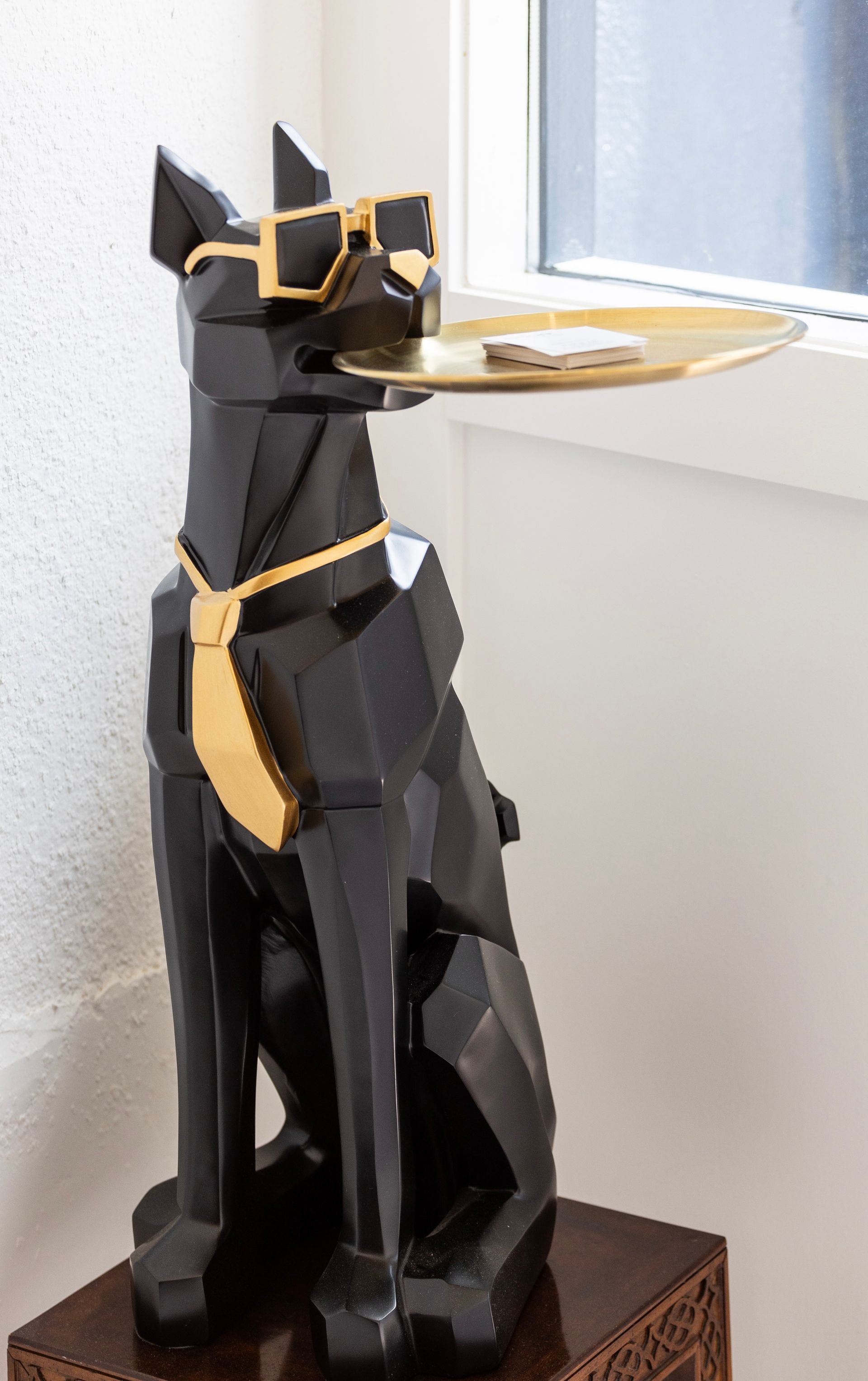 Black cat statue serving a gold tray on a wooden base, with yellow ribbon accents