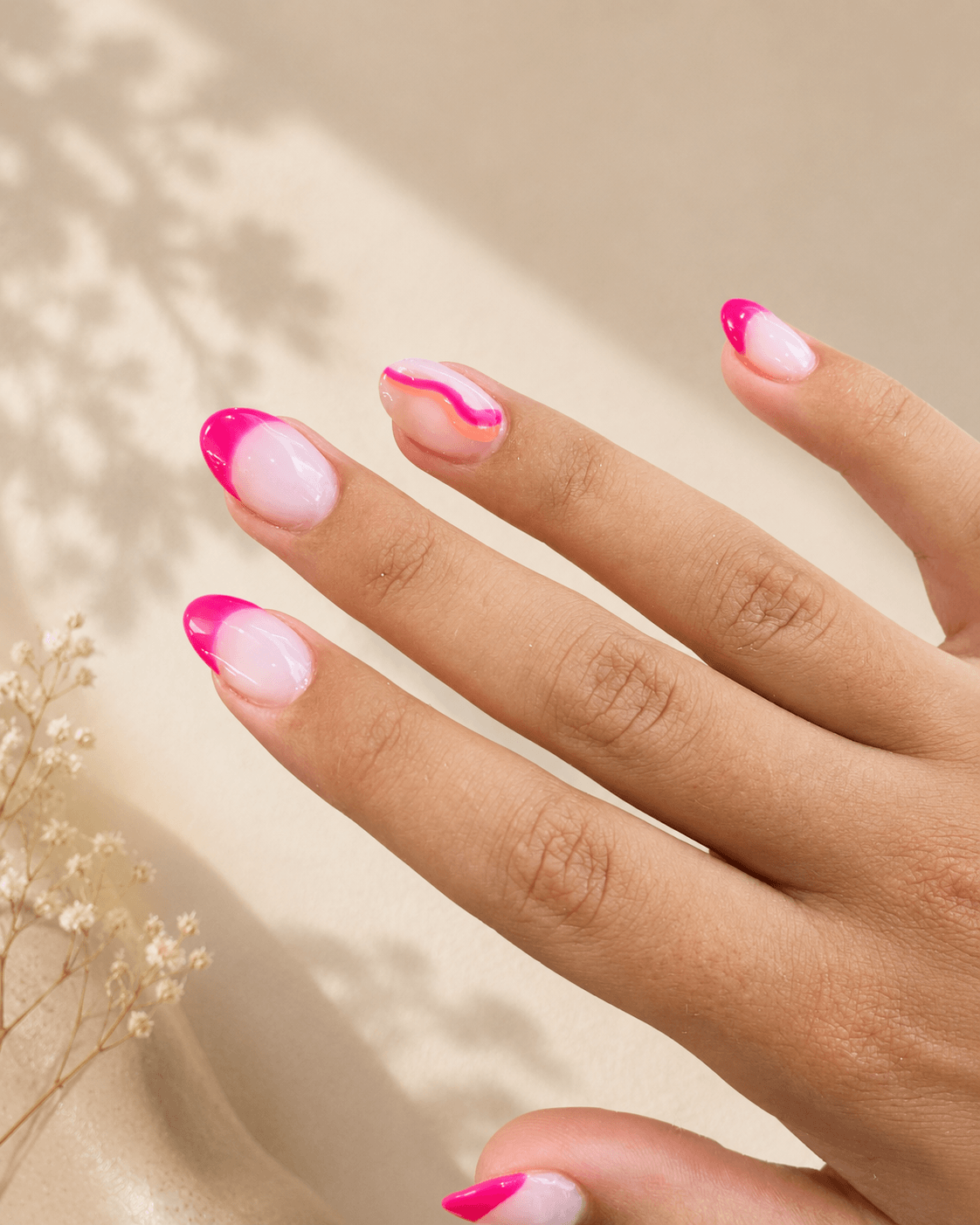 Hand with pink French-tip nails posed against a soft beige background