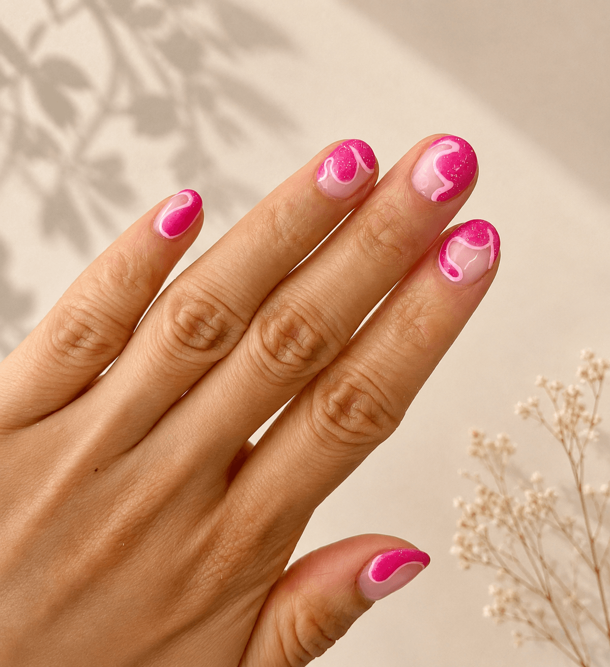 Hand with pink and white manicured nails against a beige background