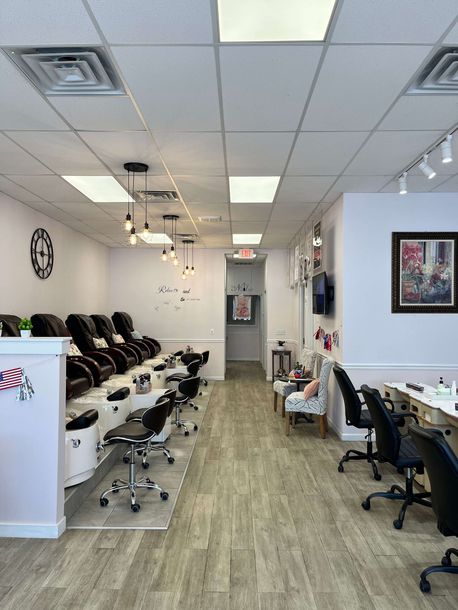 Nail salon interior with rows of black chairs, manicure tables, and bright ceiling lights