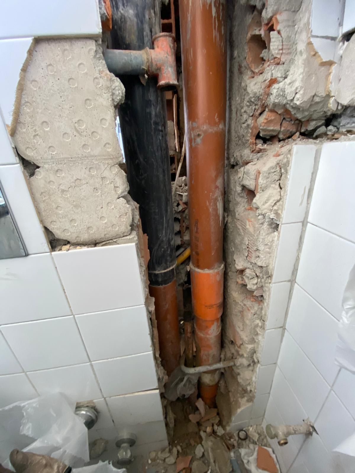 Un bagno con un buco nel muro e tubi che escono da lì