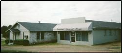 Exterior view of a light-colored building with a dark roof. "Funeral Home" awning. Overcast sky.