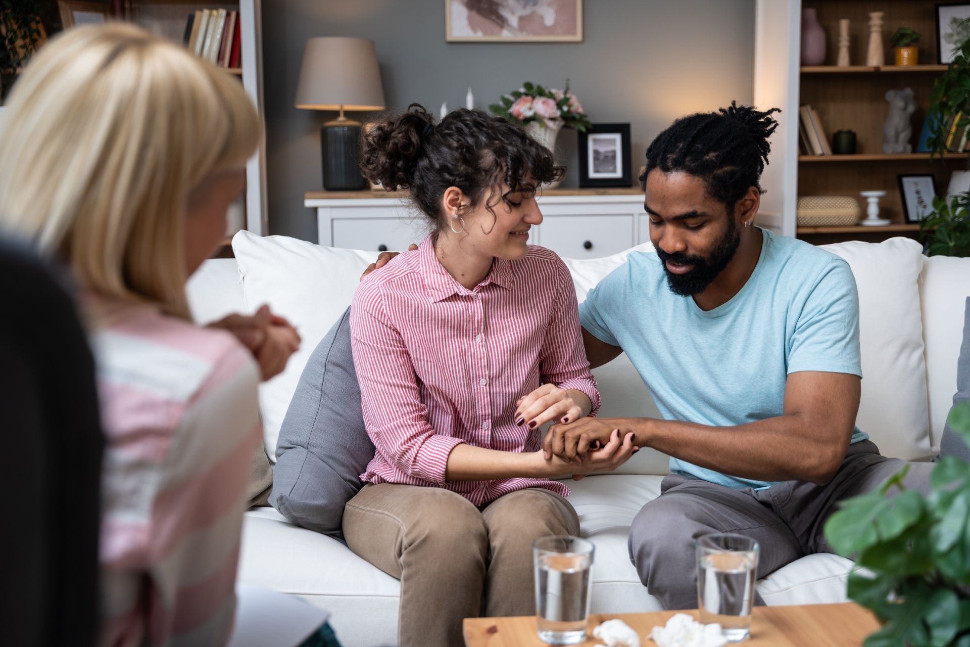 A man and a woman are sitting on a couch holding hands.