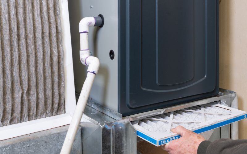 A person is changing a filter on a furnace.