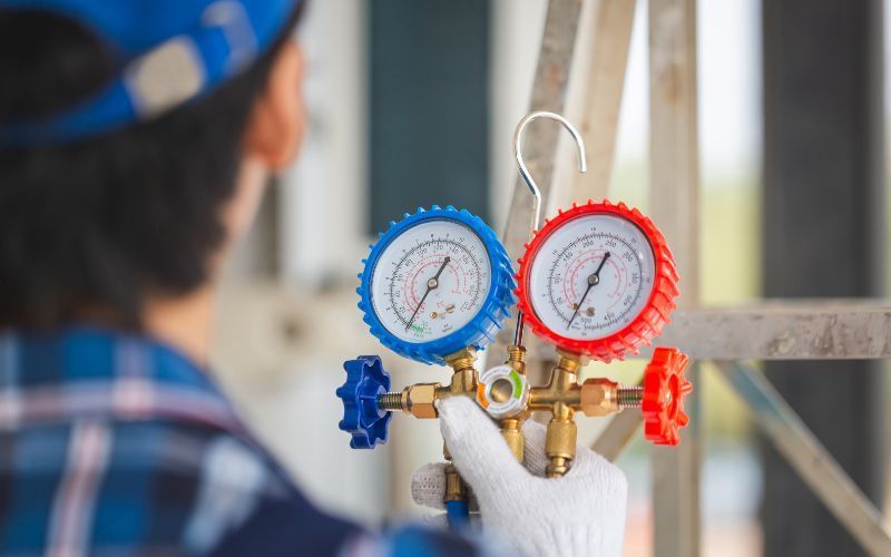 A man is holding a pressure gauge in his hand.