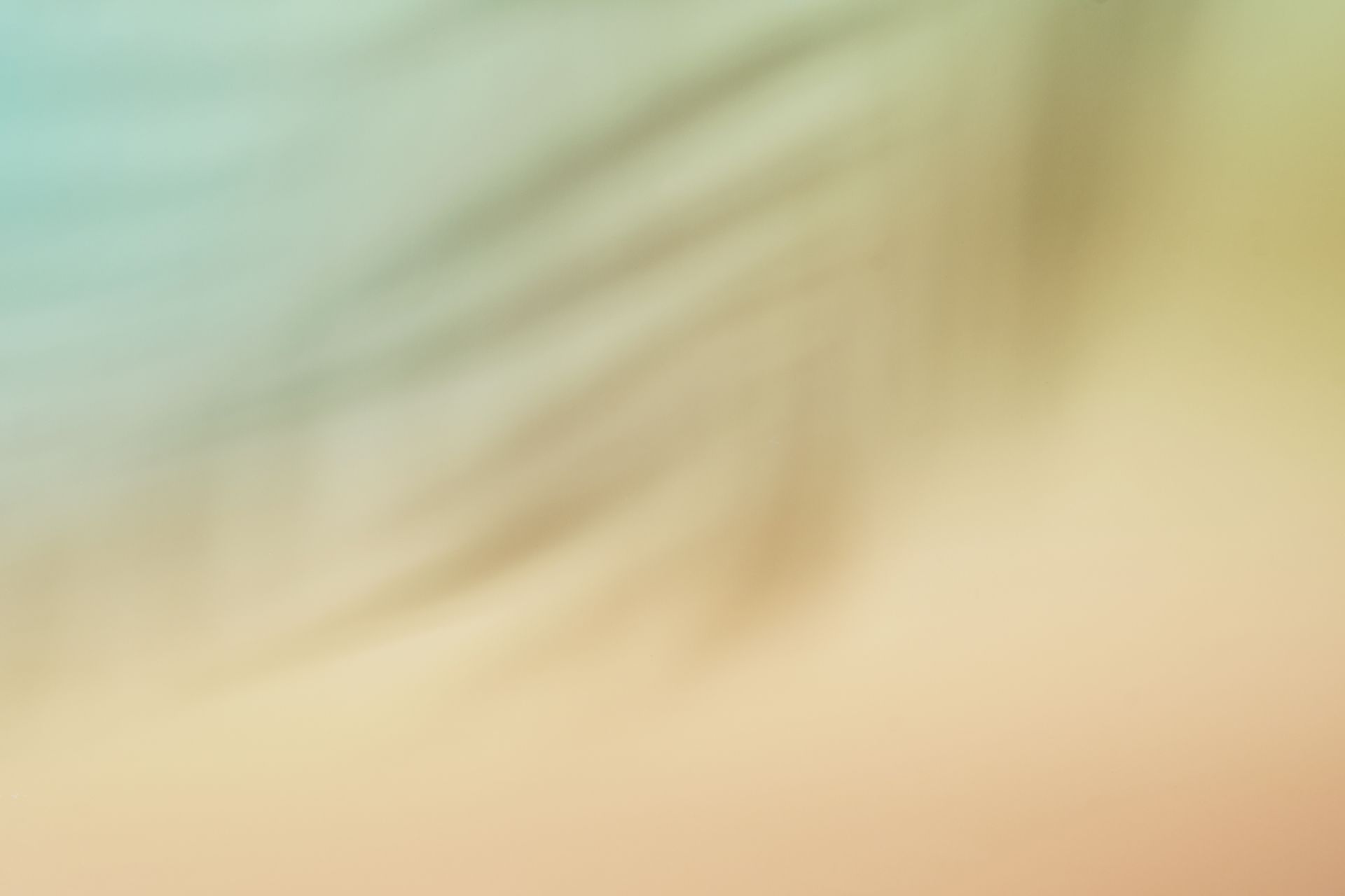 Soft abstract blur of pale green, cream, and peach tones with faint diagonal streaks