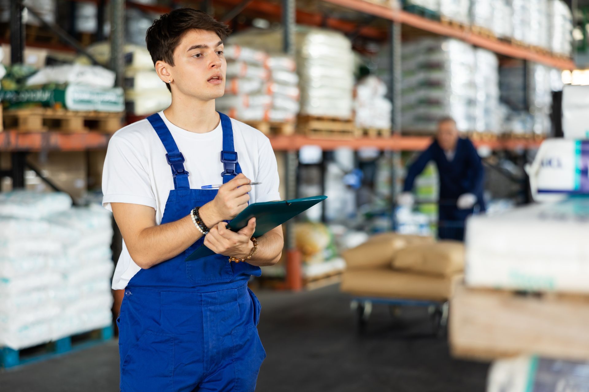An employee conducts an inventory of soil goods in a warehouse while using a clipboard. An employee conducts an inventory of soil goods in a warehouse while using a clipboard.