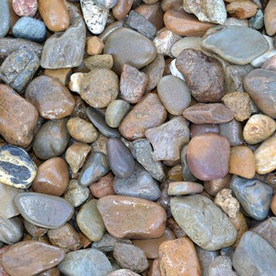 Pile of mixed-color river rocks, varying in size and shape, creating a textured surface.
