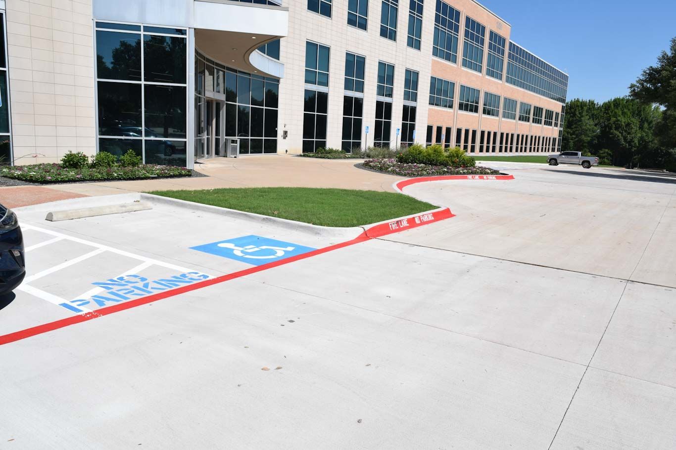 Exterior view of a building with a handicapped parking space marked with blue paint and a wheelchair symbol on the concrete pavement. Exterior view of a building with a handicapped parking space marked with blue paint and a wheelchair symbol on the concrete pavement.