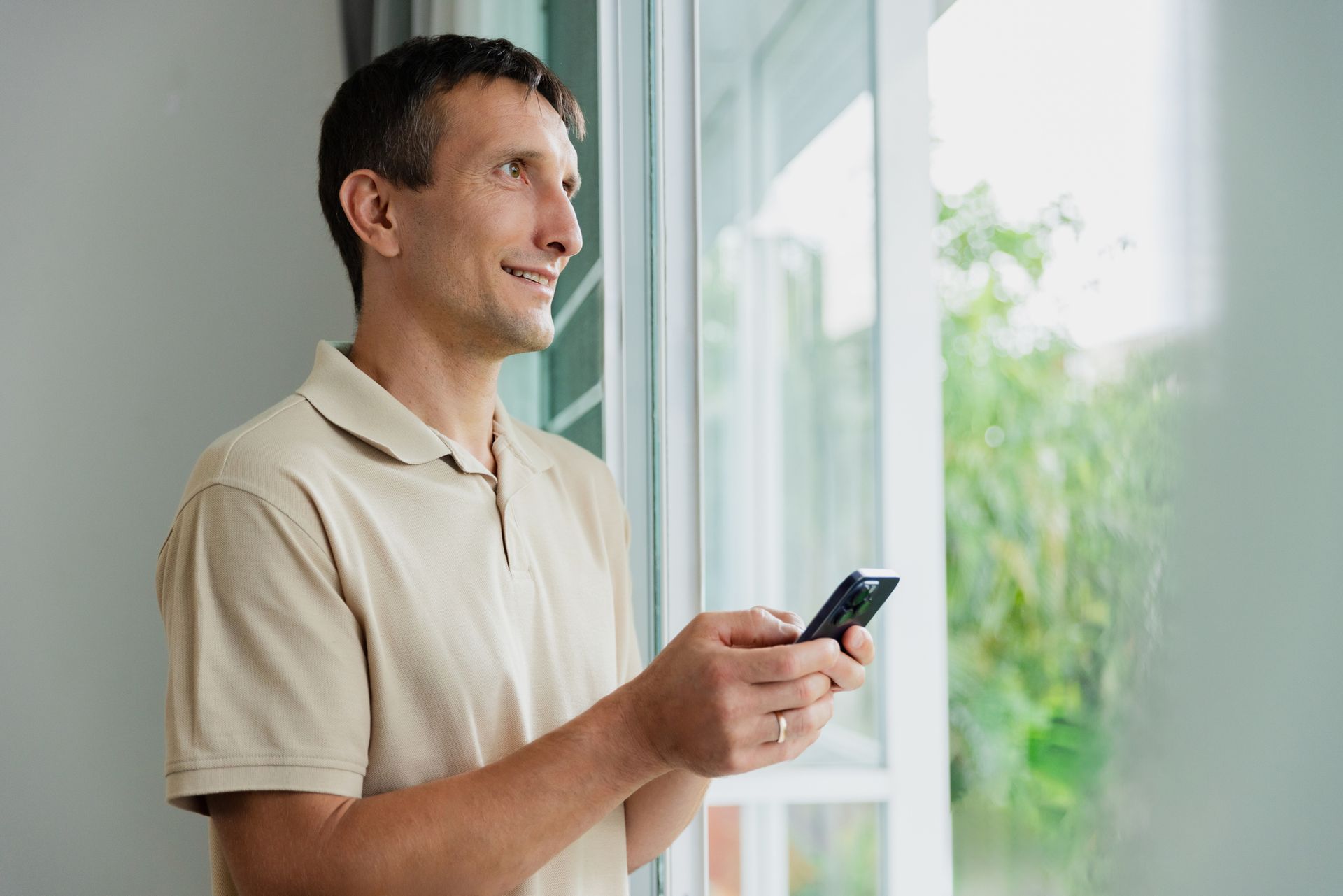 A man is standing in front of his window calling for window tinting services.
