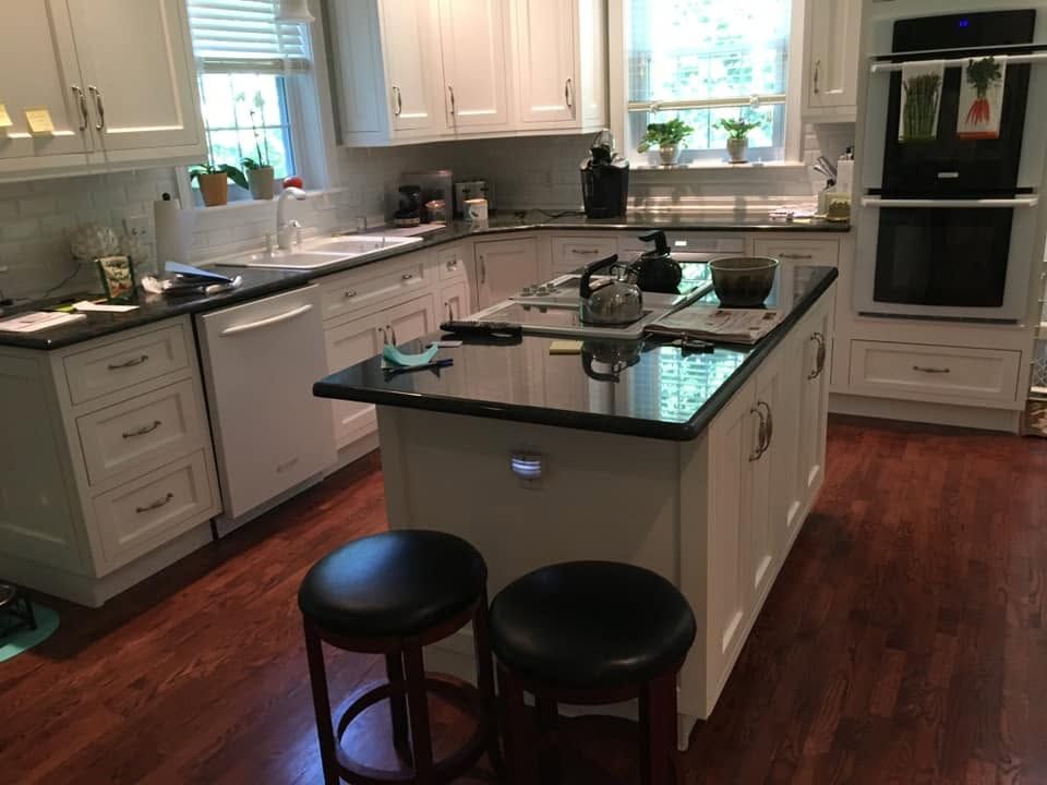 Bright modern kitchen with black island, two stools, and stainless appliances