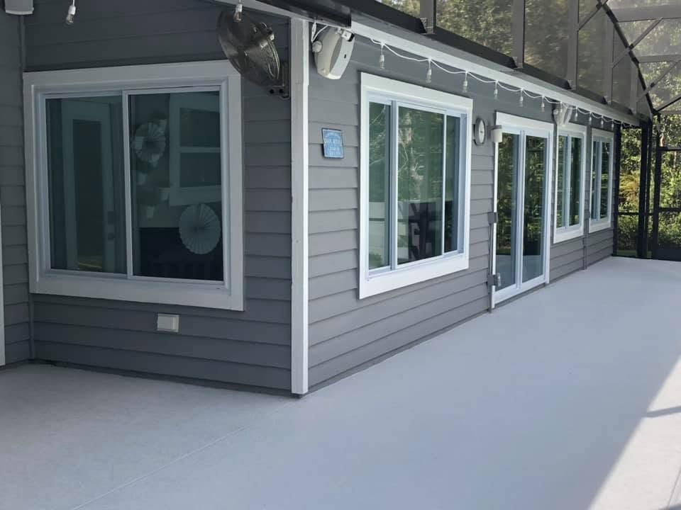 Snow-covered patio beside a gray house with white-trimmed windows and sliding glass doors