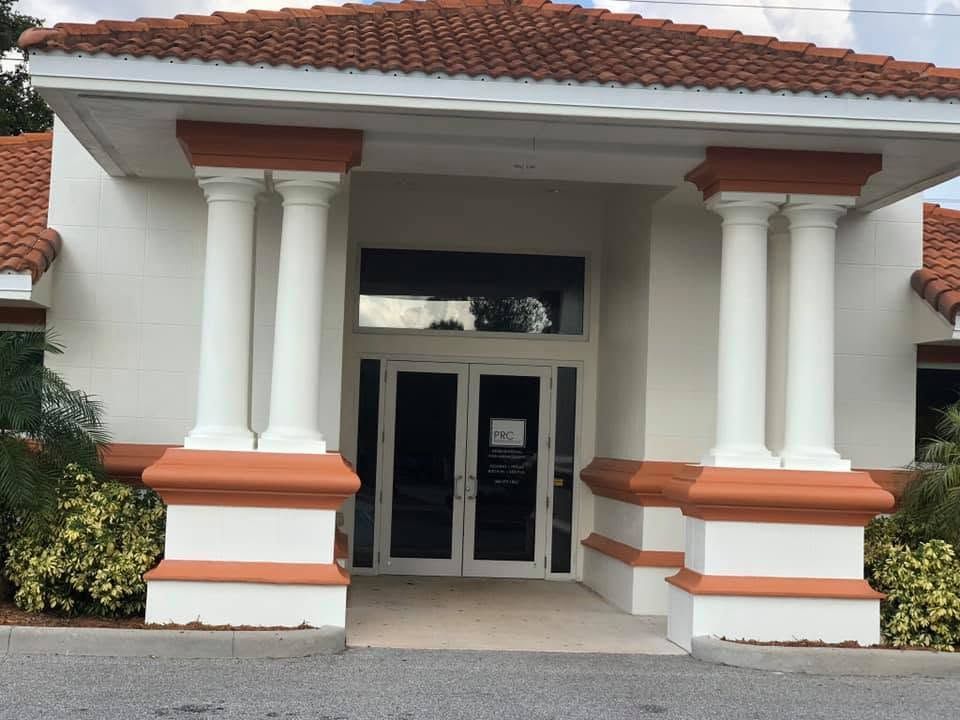 Front entrance of a white building with red tile roof and large white columns.