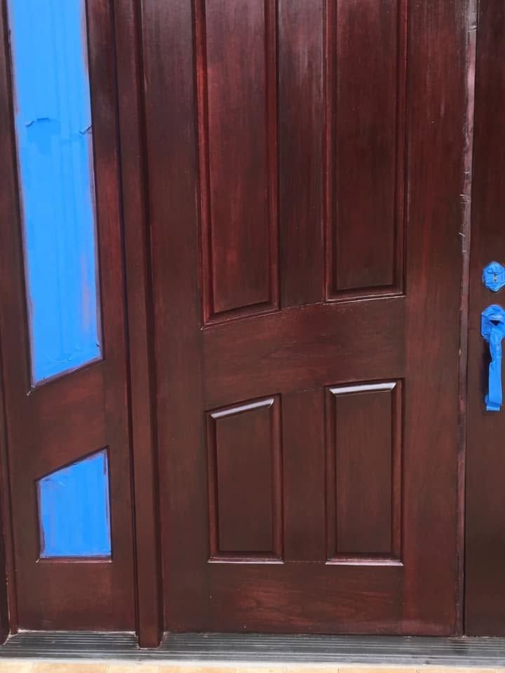 Brown wooden front door with blue side panels and a blue handle lock