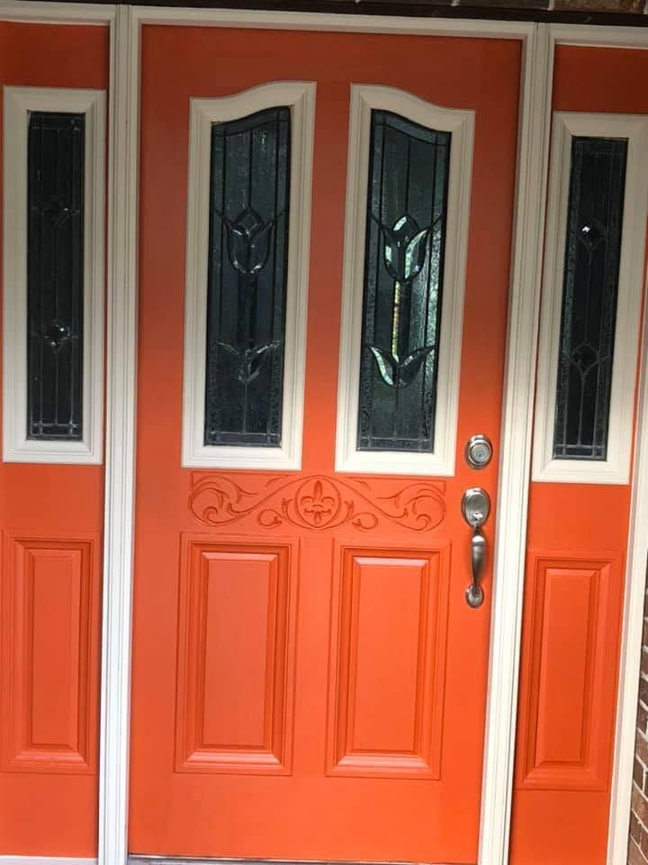 Orange front door with decorative glass panels and silver handle