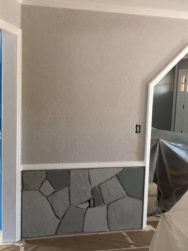 Gray wall with stone veneer base, white trim, and a taped-off doorway in a home interior