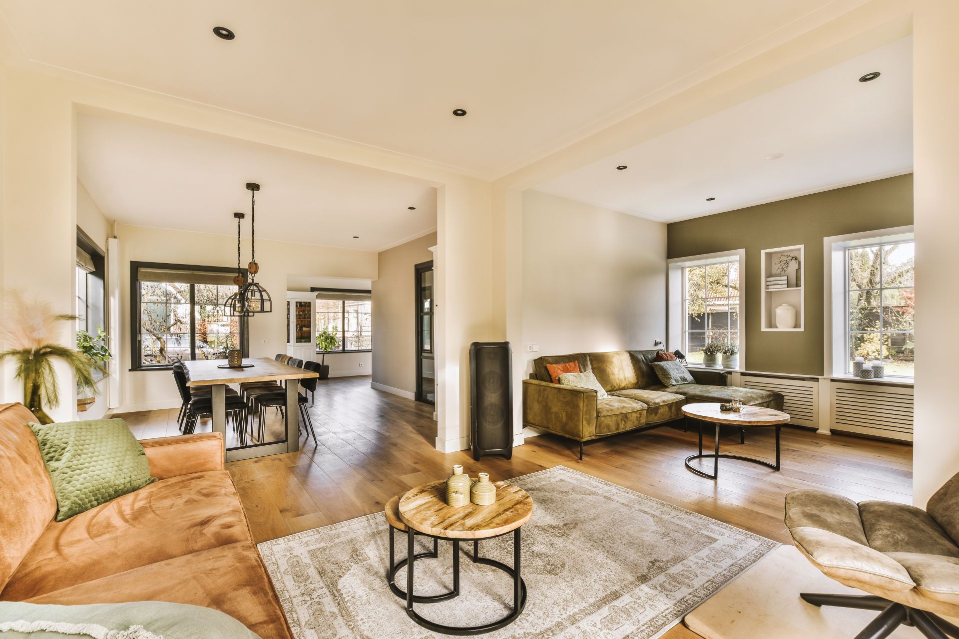 Bright open living room and dining area with neutral decor, wood floors, and large windows