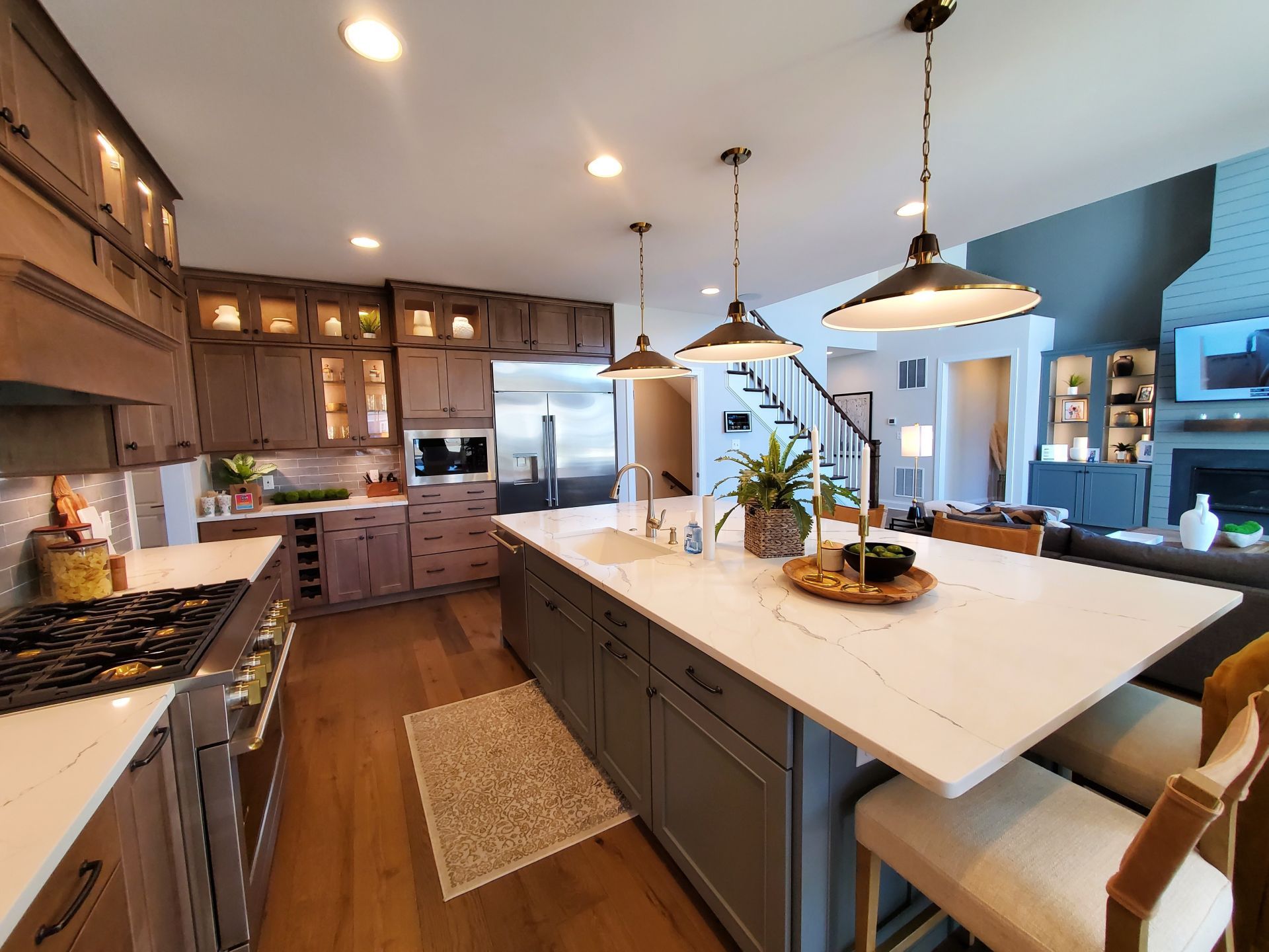 Modern kitchen with large island, pendant lights, stainless appliances, and warm wood cabinetry