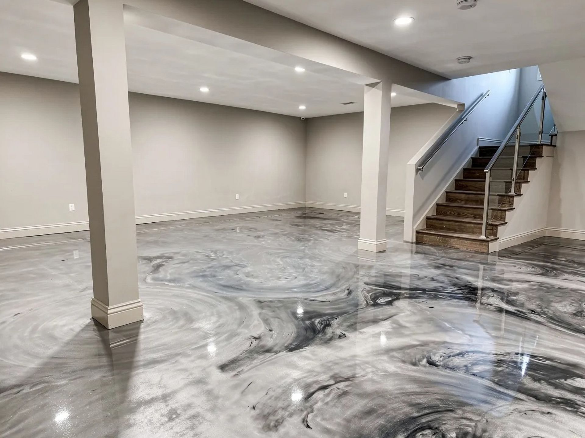 Flooded basement with swirling muddy water, white walls, columns, and a staircase at right