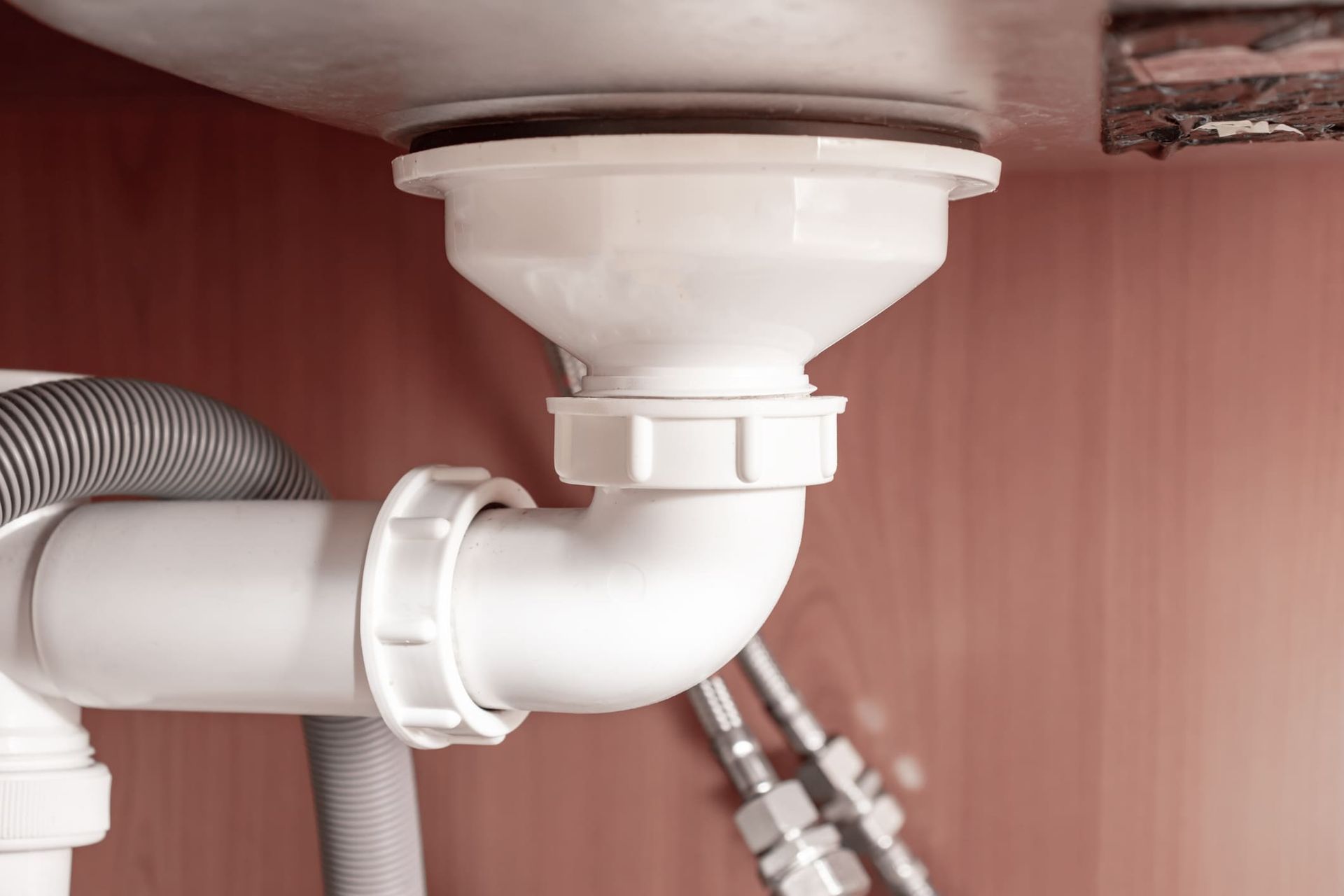 A close up of a sink drain with a hose attached to it.
