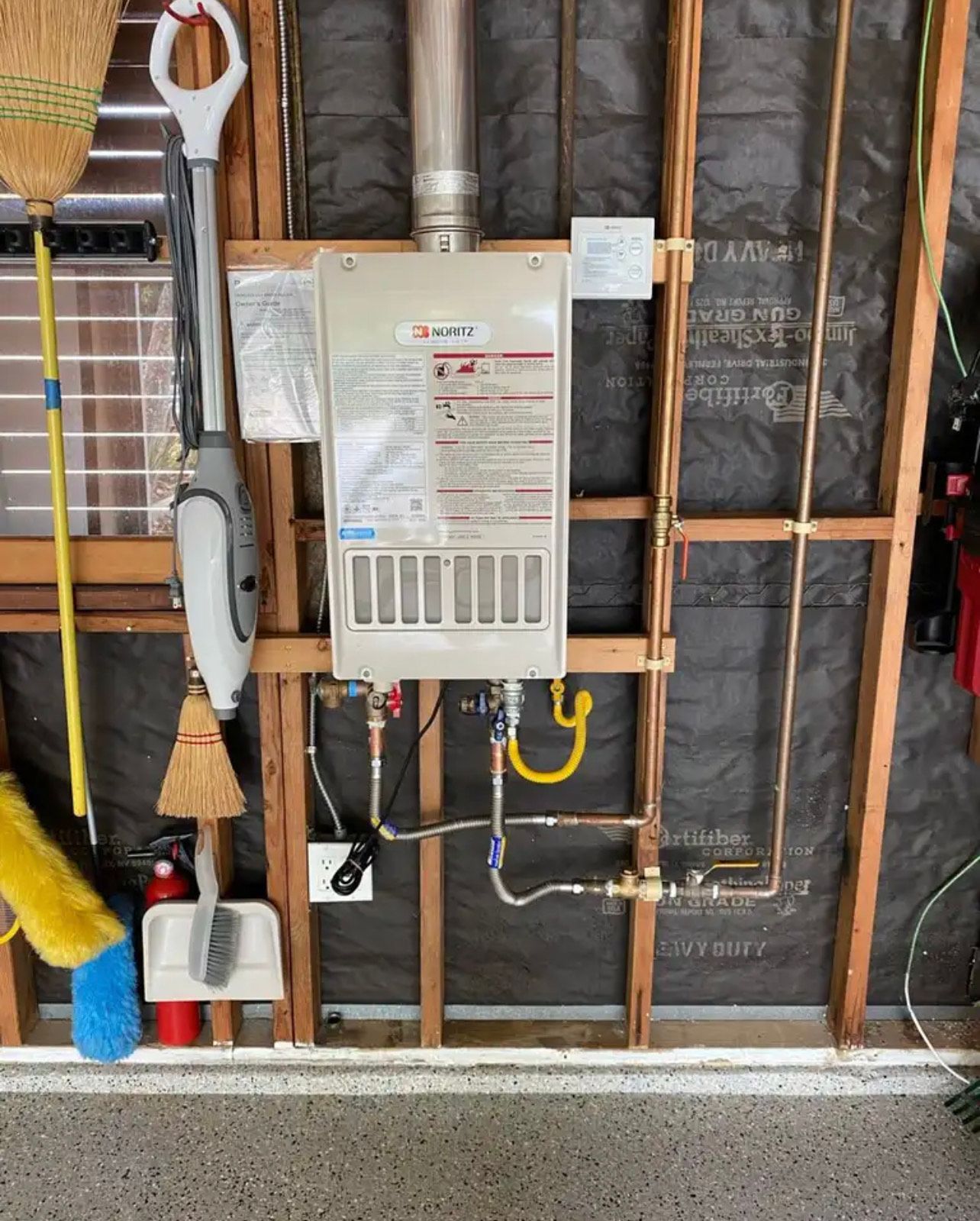 A water heater is hanging on a wall in a garage.