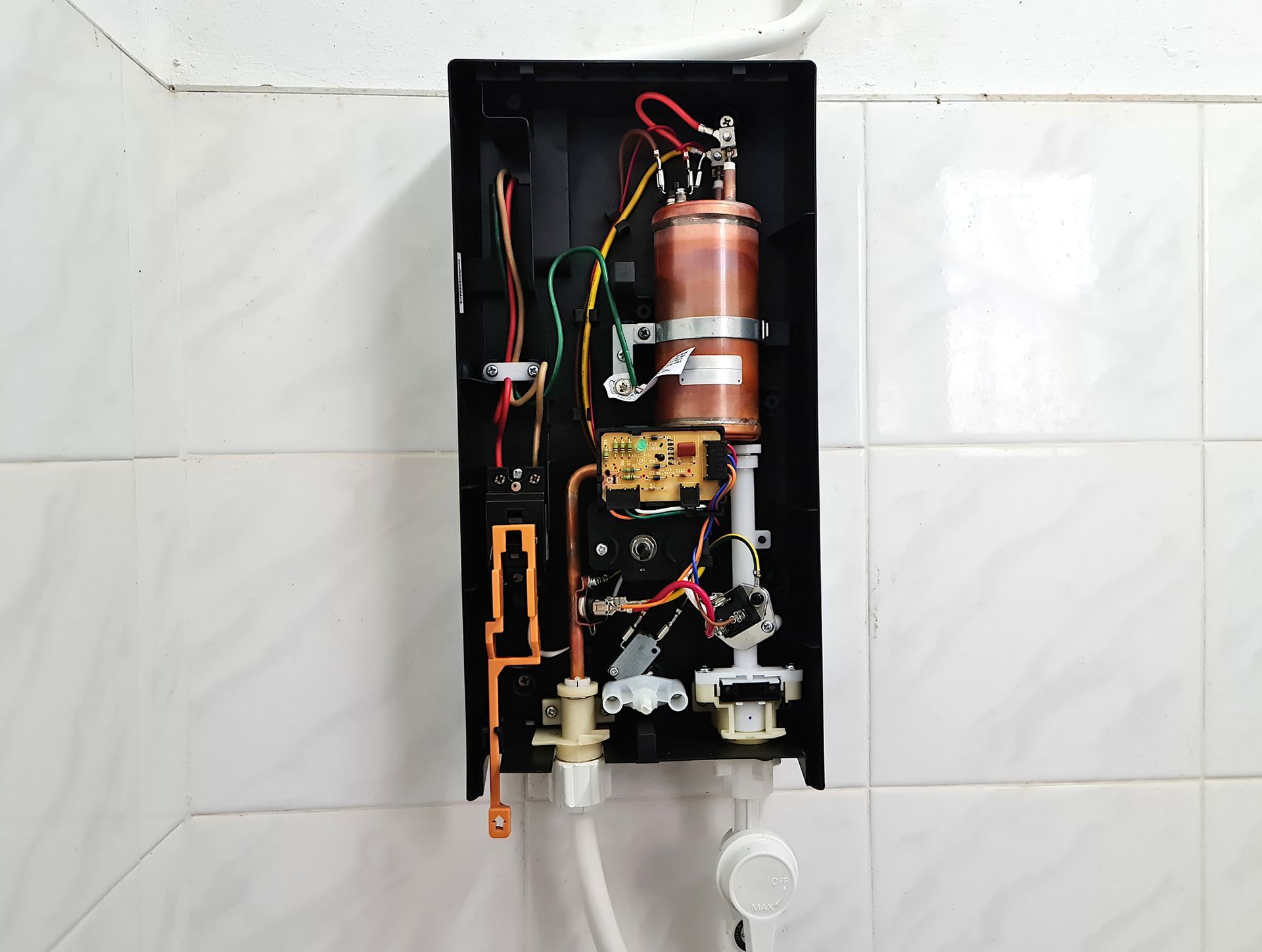 A water heater is hanging on a wall in a bathroom.