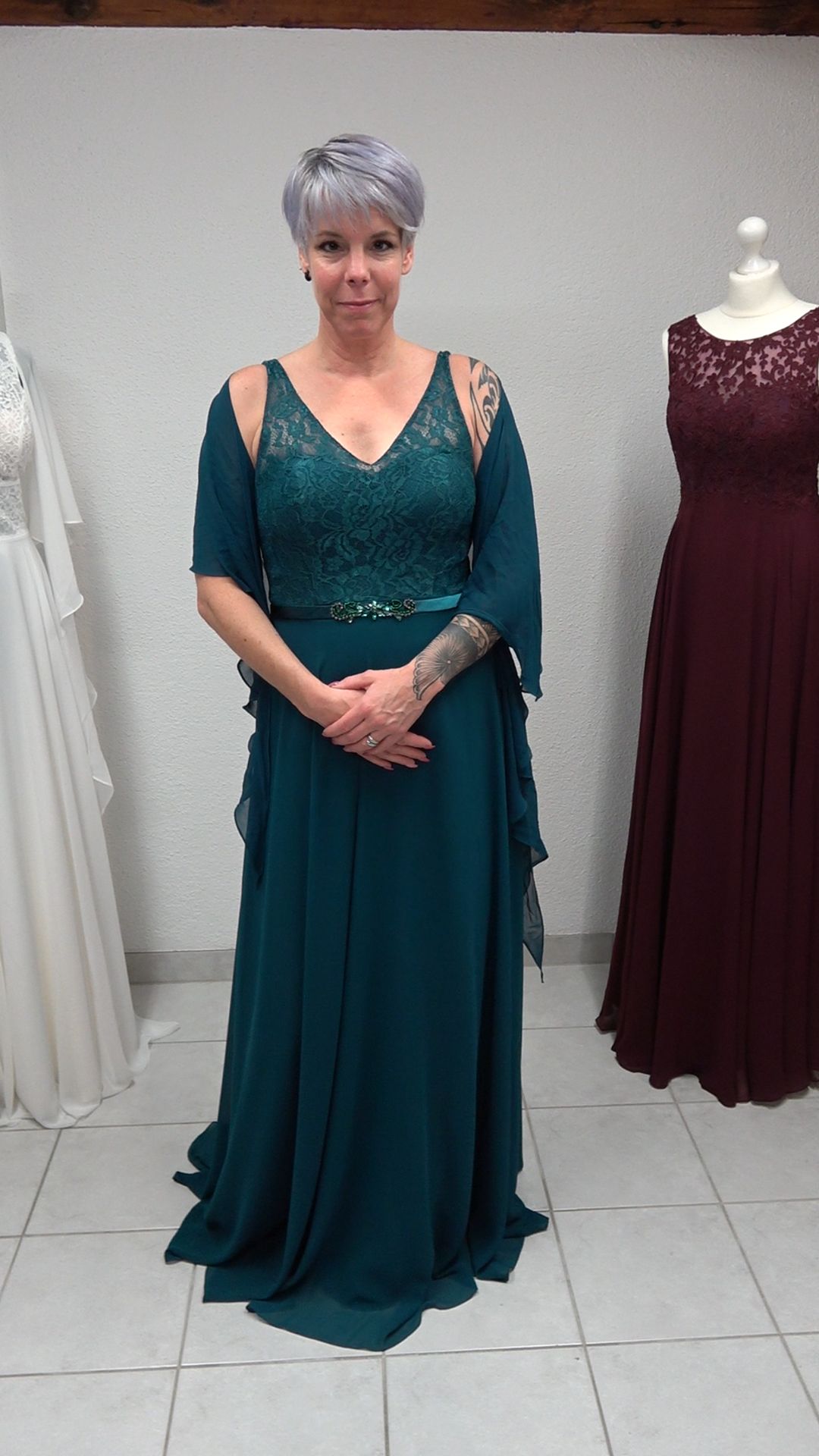 Eine Frau in einem grünen Kleid steht vor einer Schaufensterpuppe.