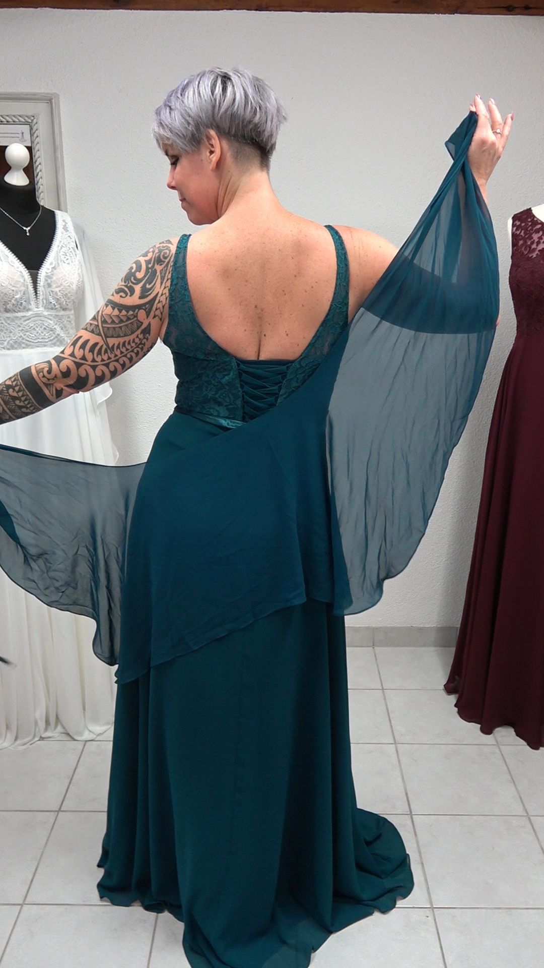 Der Rücken einer Frau, die ein grünes Kleid mit Umhang trägt.