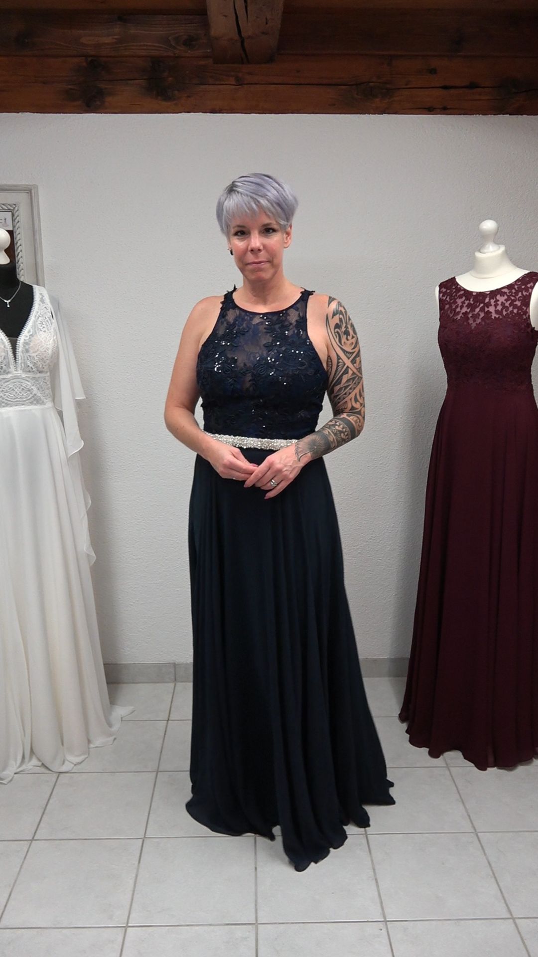 Eine Frau in einem langen schwarzen Kleid steht vor einer Schaufensterpuppe.