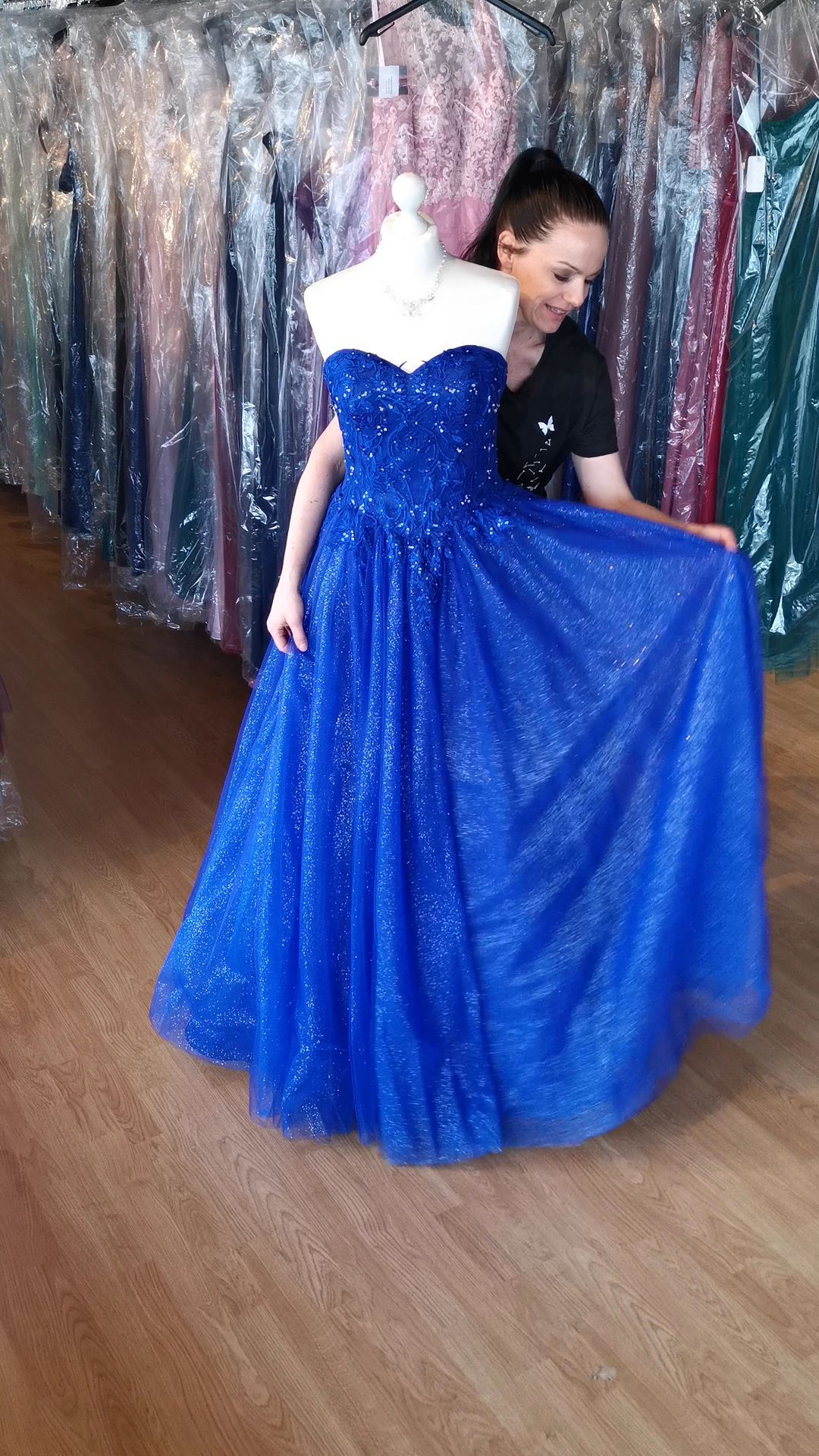 Eine Frau probiert an einer Schaufensterpuppe ein blaues Kleid an.