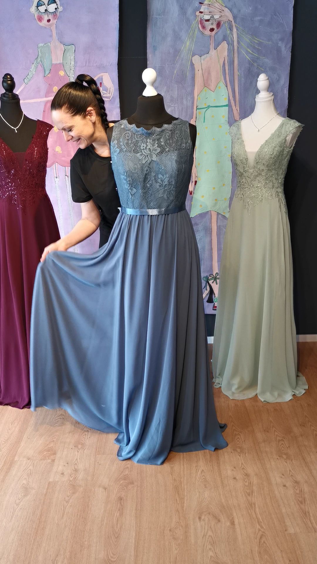 Eine Frau in einem blauen Kleid steht neben einer Schaufensterpuppe.