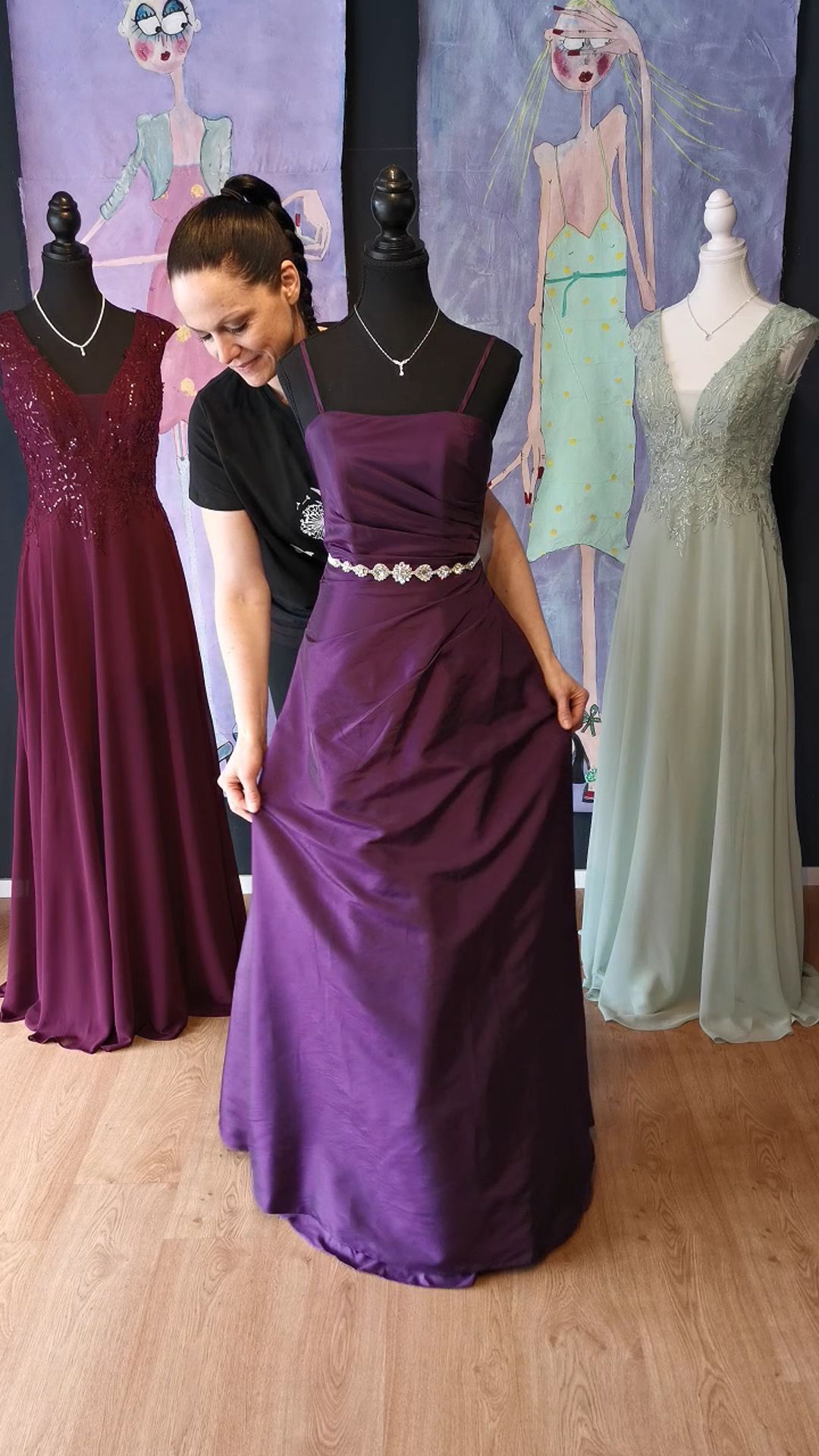 Eine Frau probiert an einer Schaufensterpuppe ein lila Kleid an