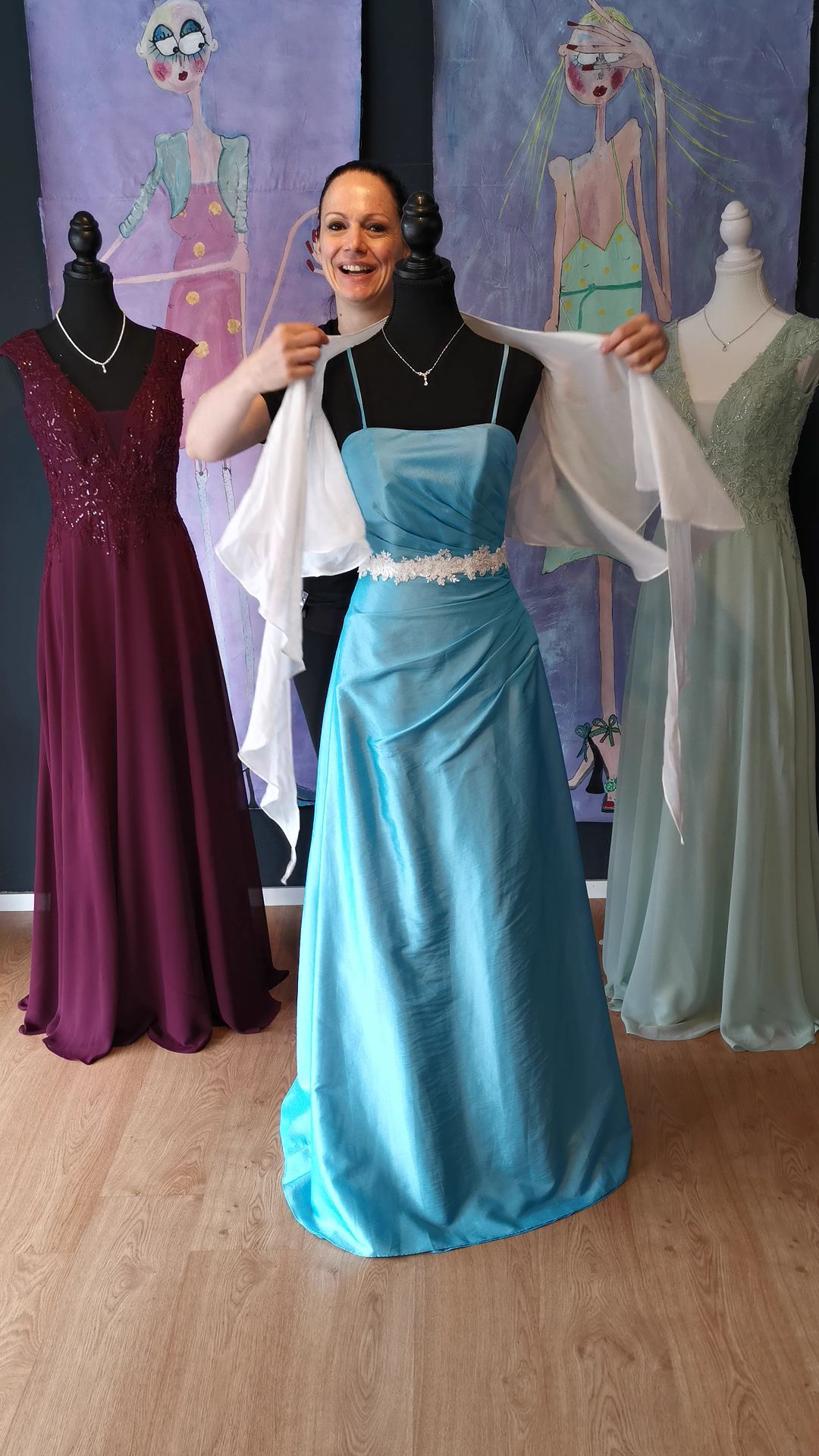 Eine Frau in einem blauen Kleid steht neben einer Schaufensterpuppe.