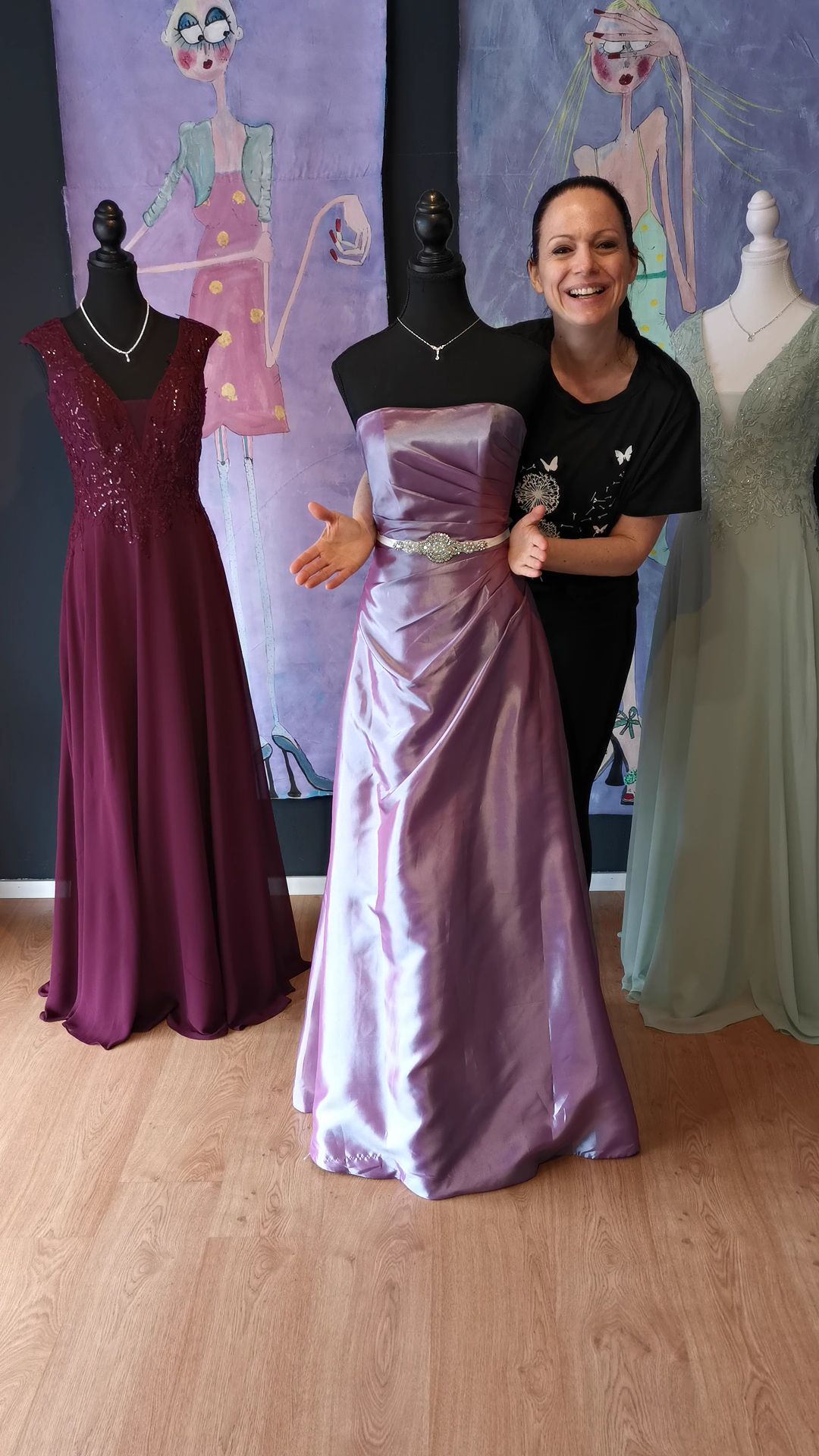 Eine Frau in einem lila Kleid steht neben einer Schaufensterpuppe.
