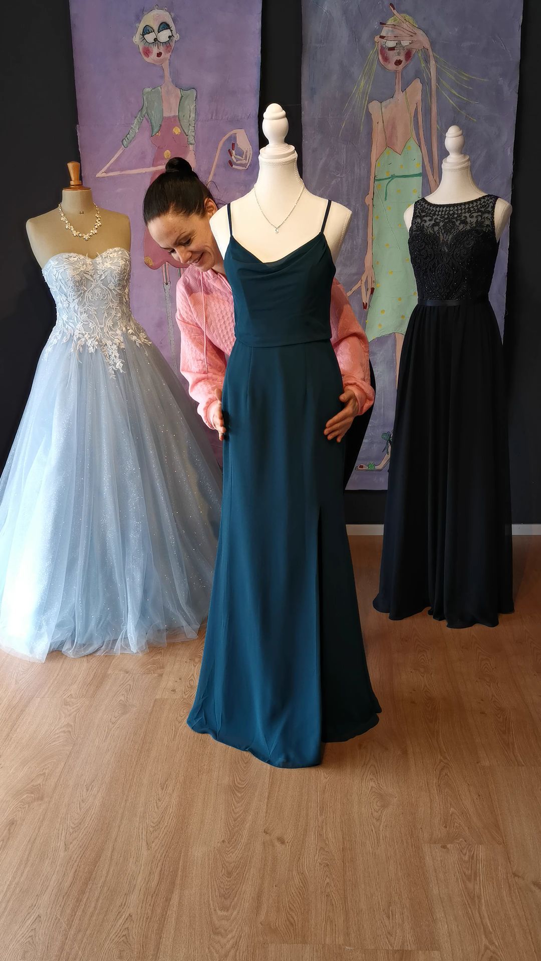 Eine Frau richtet in einem Geschäft ein Kleid an einer Schaufensterpuppe.