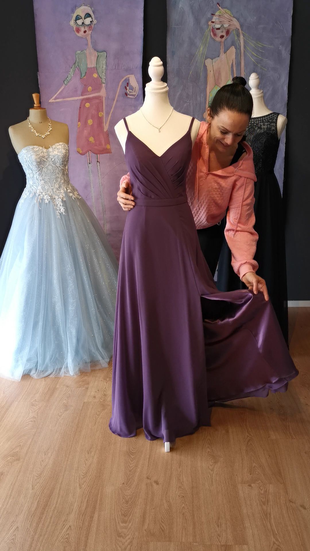 Eine Frau in einem lila Kleid steht neben einer Schaufensterpuppe.
