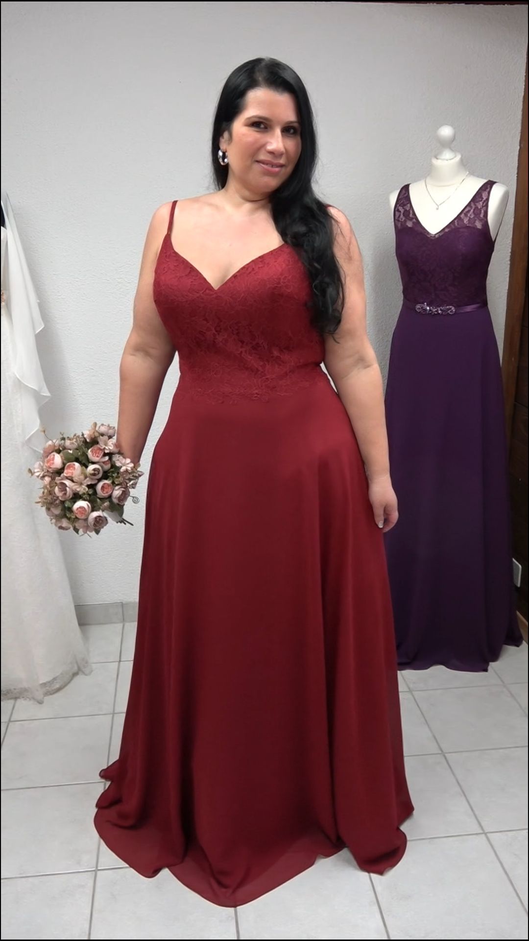 Eine Frau in einem langen roten Kleid hält einen Blumenstrauß.