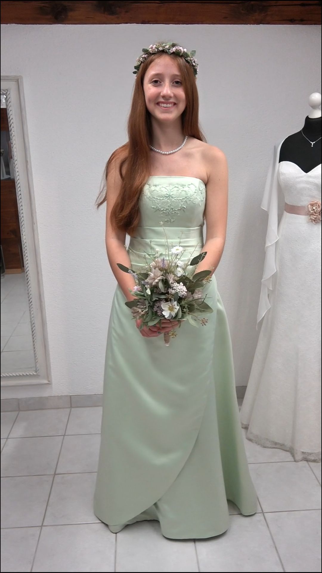 Eine Frau in einem grünen Kleid hält einen Blumenstrauß.