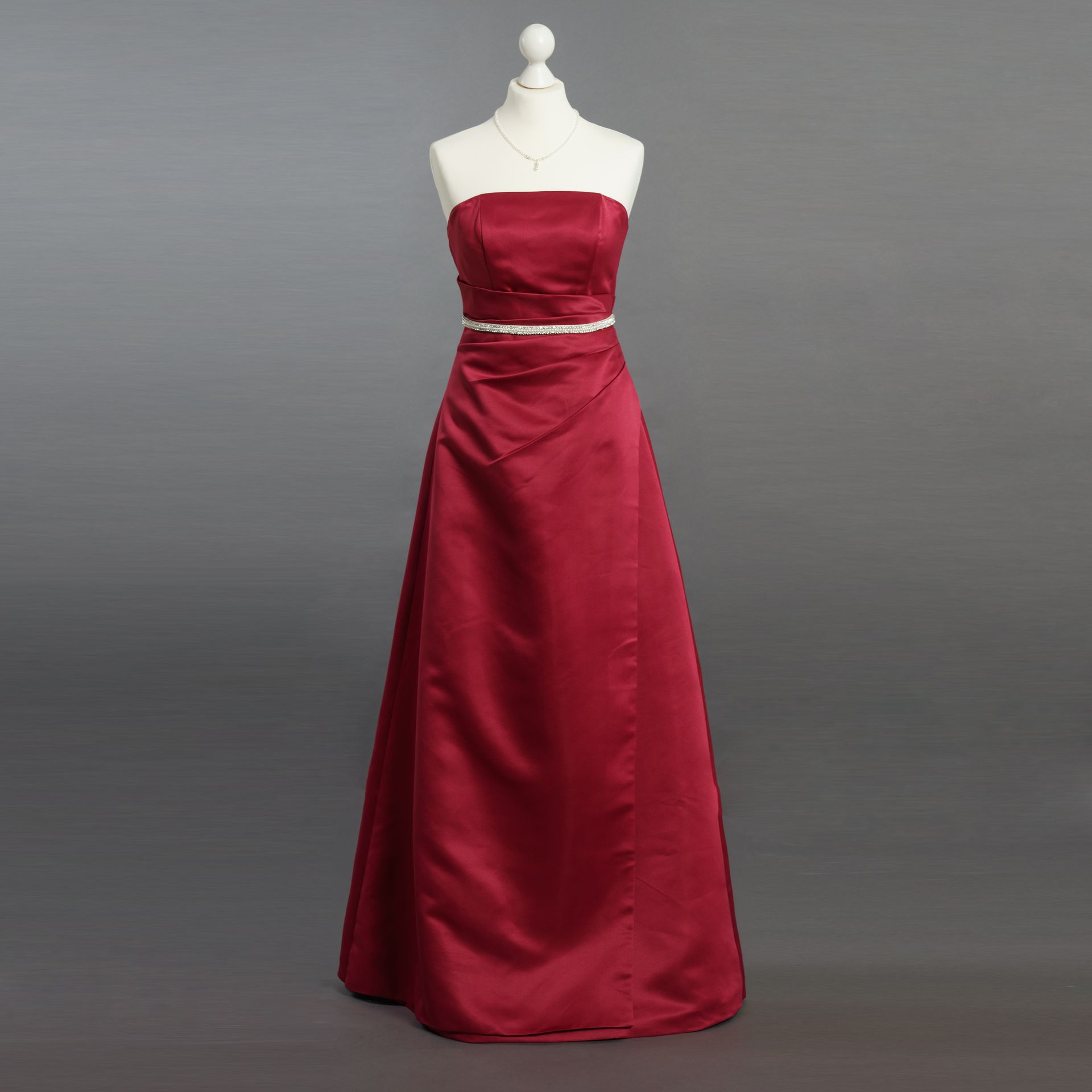 Ein rotes trägerloses Kleid hängt an einer Schaufensterpuppe