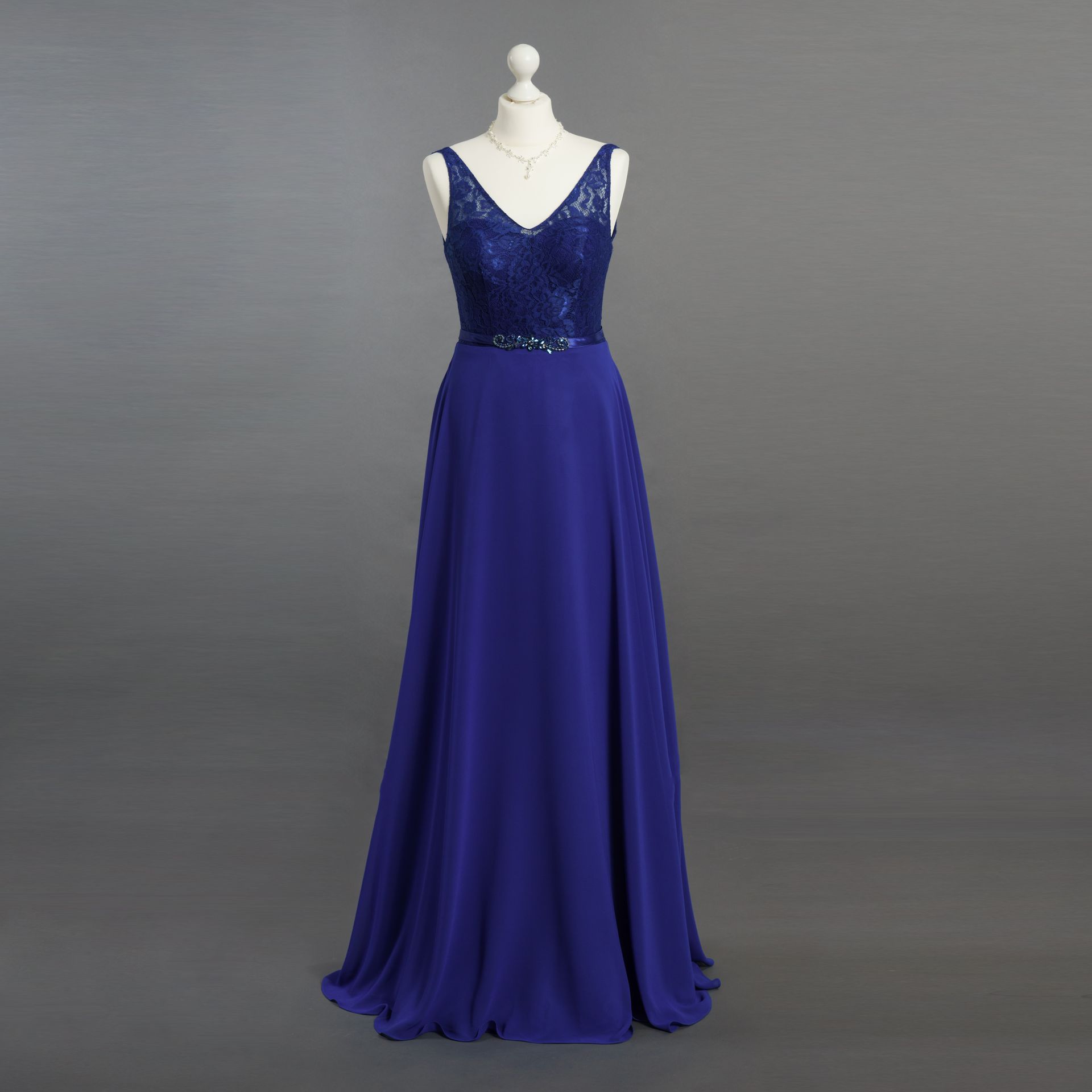 Ein blaues Kleid hängt an einer Schaufensterpuppe vor einem grauen Hintergrund