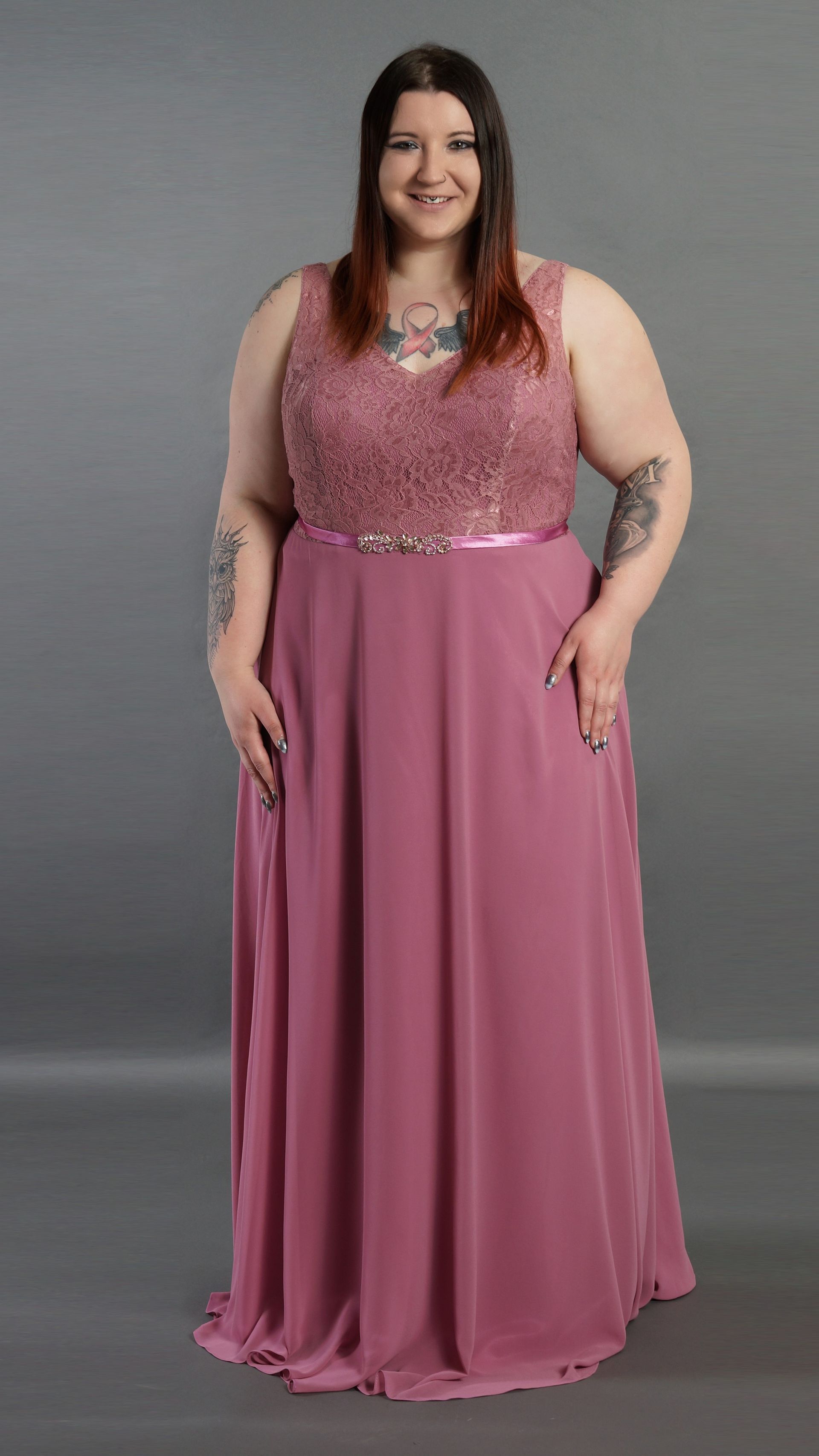 Eine Frau mit Übergröße trägt ein langes rosa Kleid.