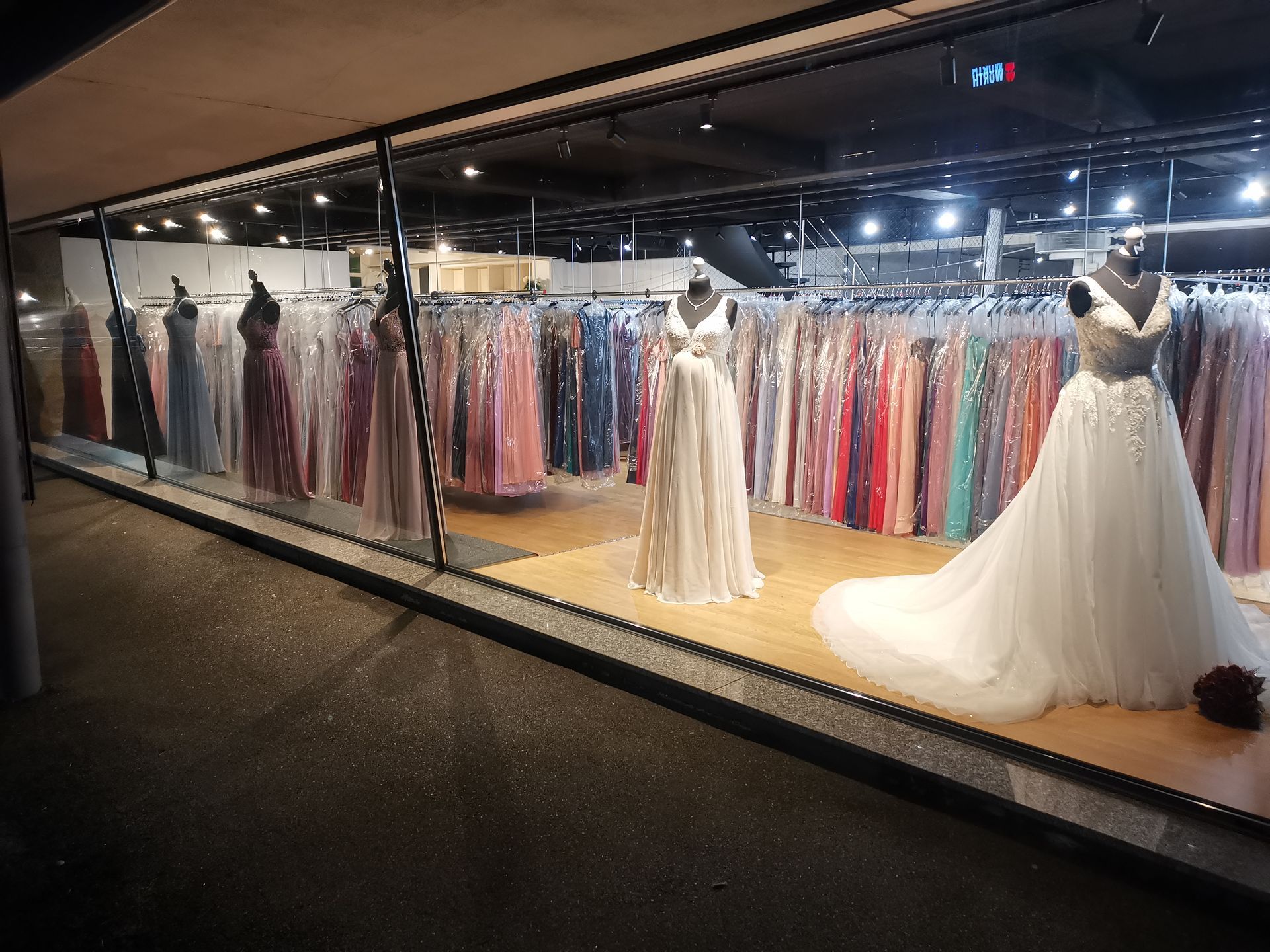 In einem Schaufenster ist eine Reihe Brautkleider ausgestellt.