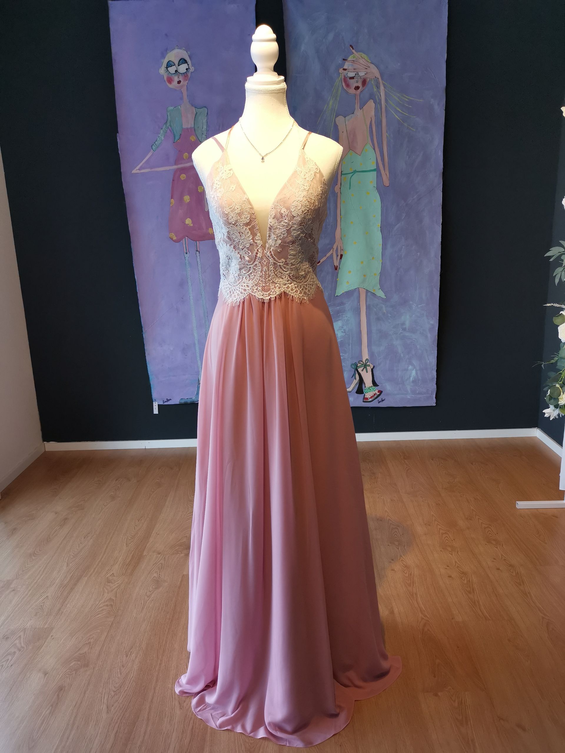 Ein rosa Kleid hängt an einer Schaufensterpuppe in einem Raum