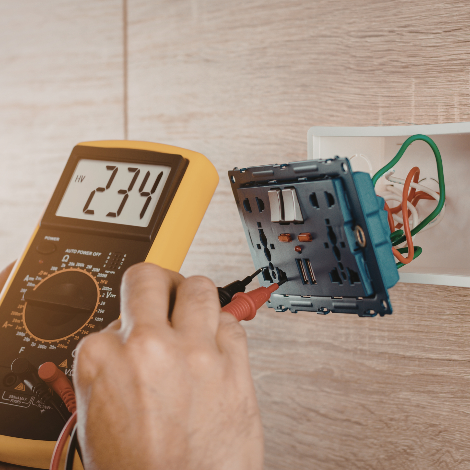 Person testing electrical wiring with a multimeter, displaying a reading of 234 volts.