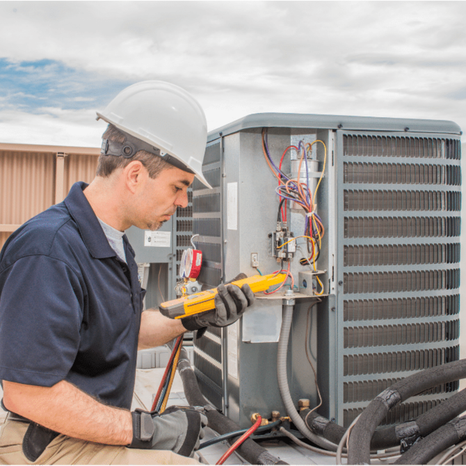 HVAC technician in a hard hat inspects air conditioning unit with a multimeter on a rooftop.