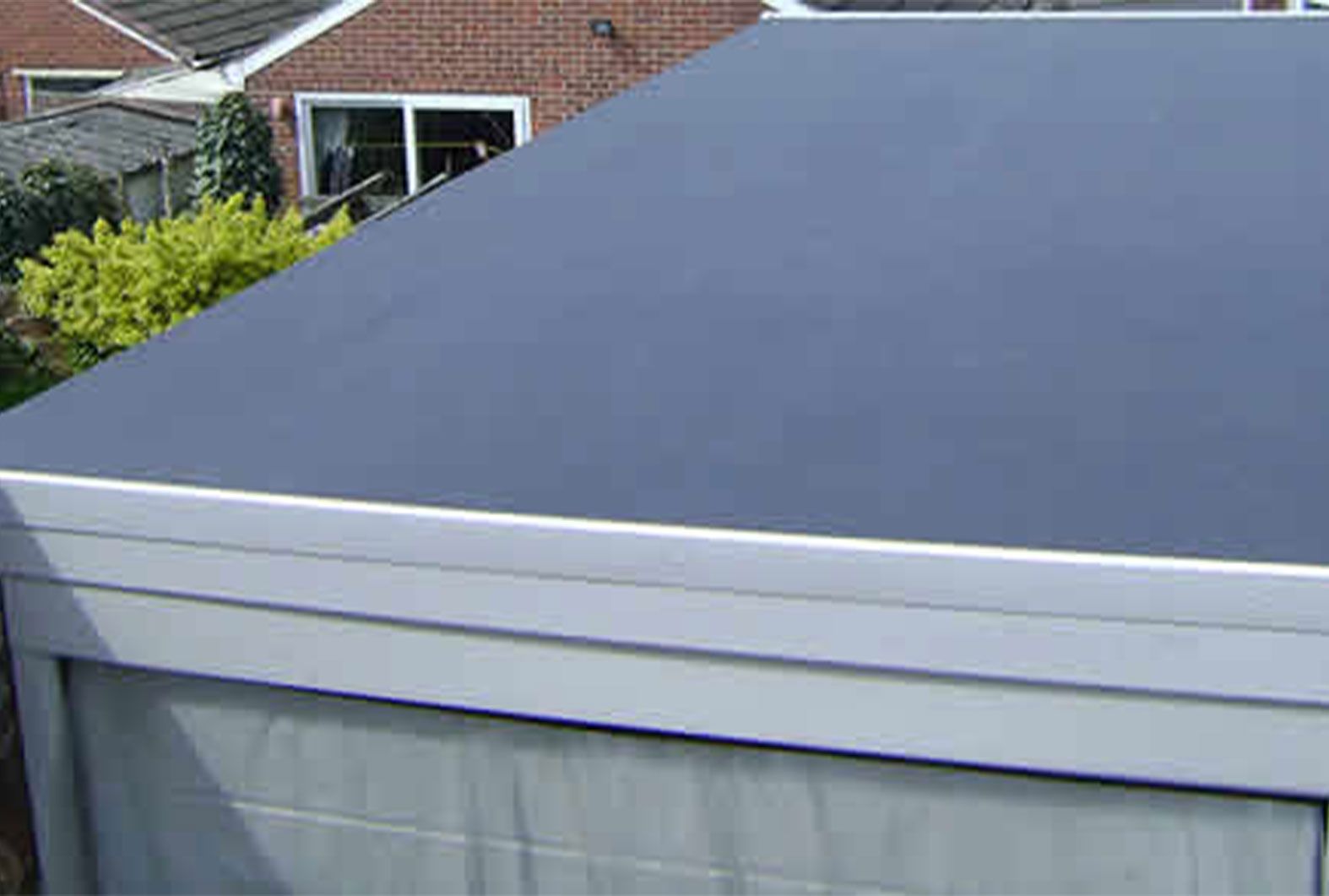 Flat, dark gray roof on a garage with white trim.